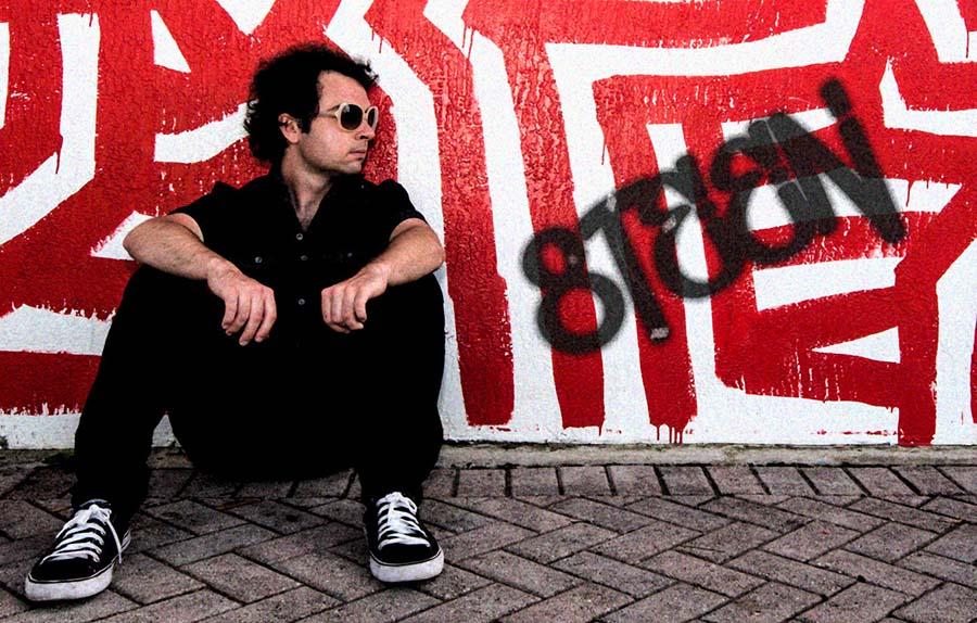 man-sitting-on-the-ground-in-front-of-graffiti-wall