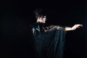 Woman dressed in black dancing in a dark room