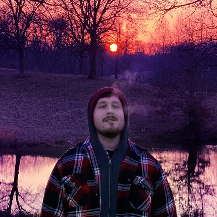 man standing in front of a lake at sunset