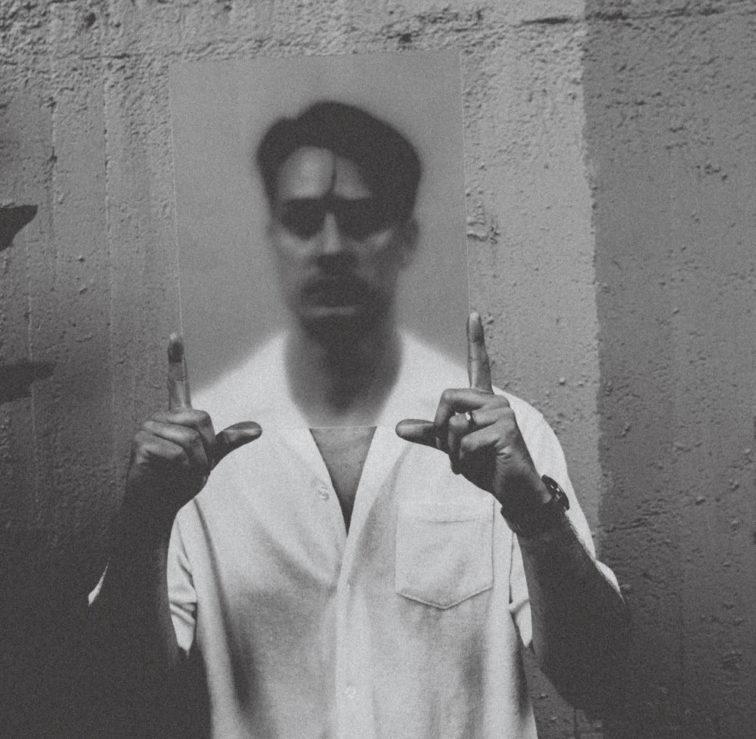 black and white photo of man standing in front of a wall