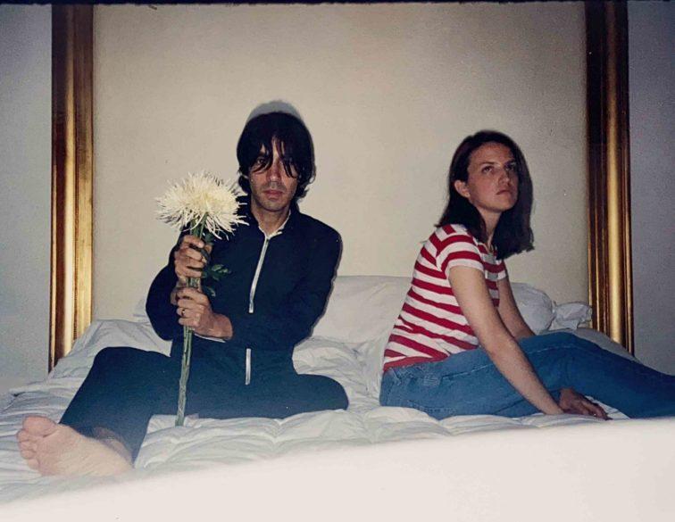 man and woman sitting on a bed