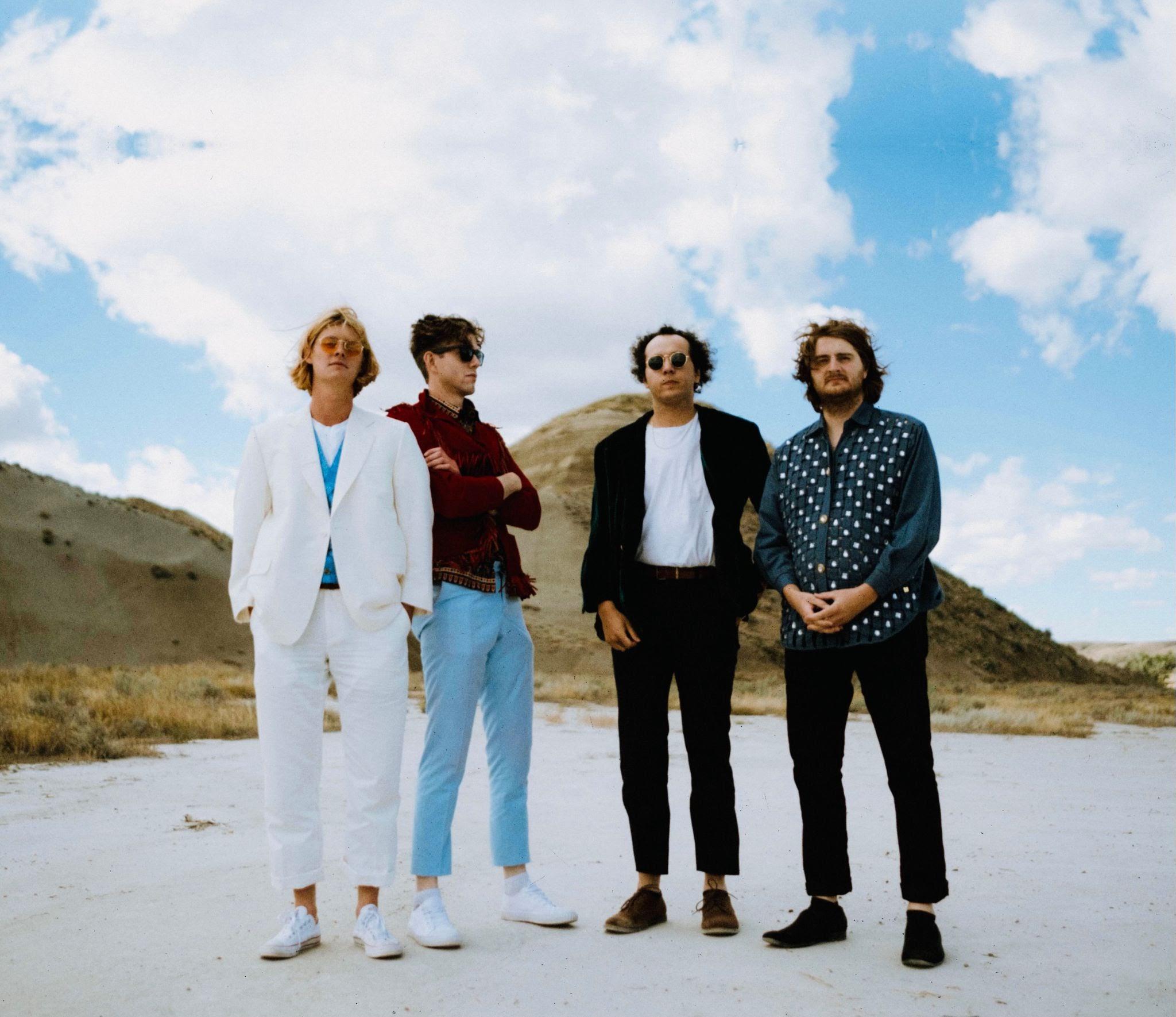 4 band members in front of desert mountains