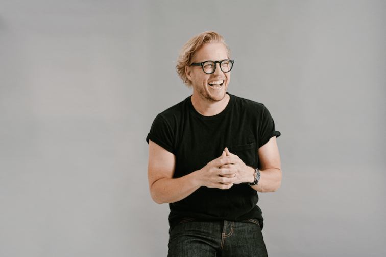 man standing in front of a grey wall smiling