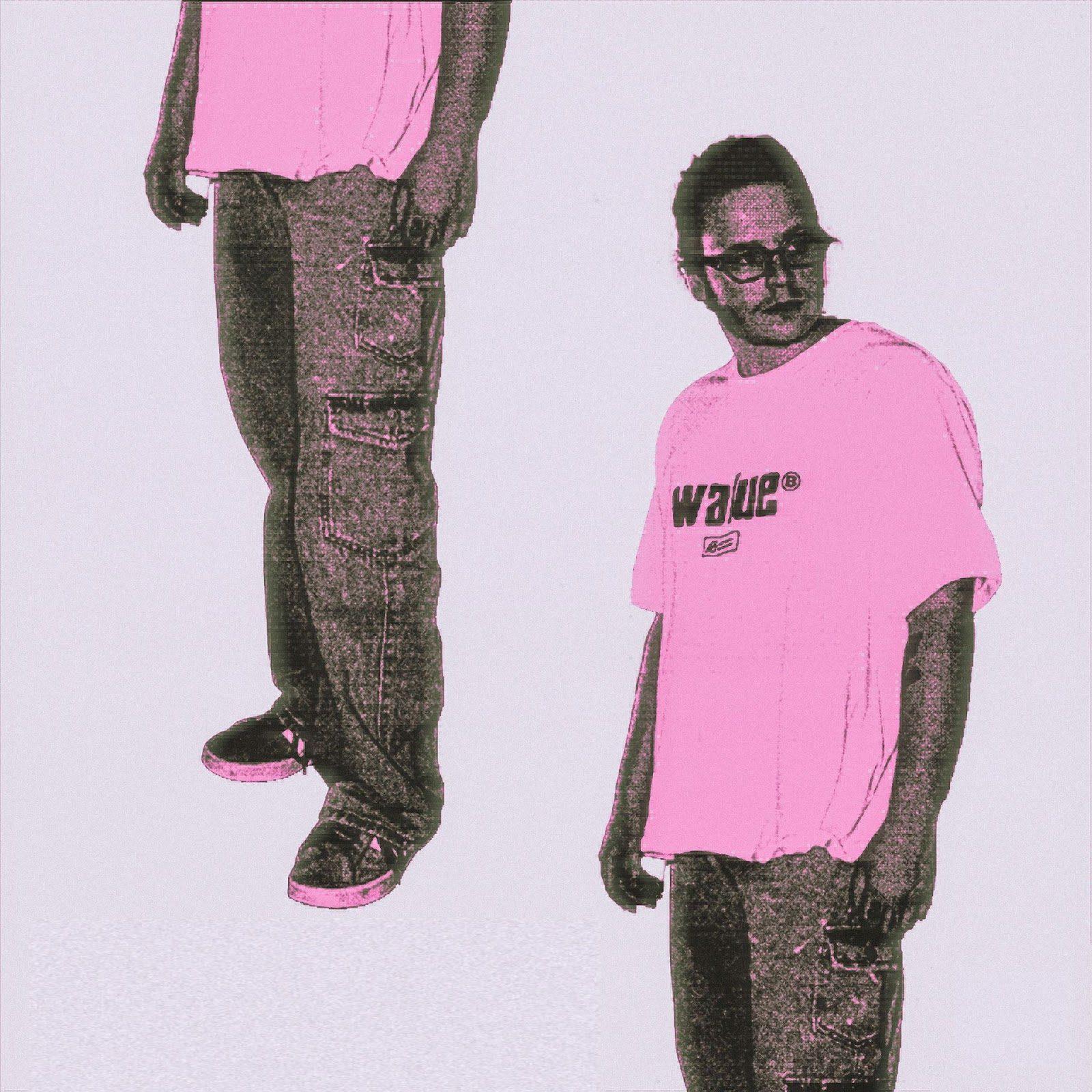 man standing in front of a white wall wearing a pink t-shirt