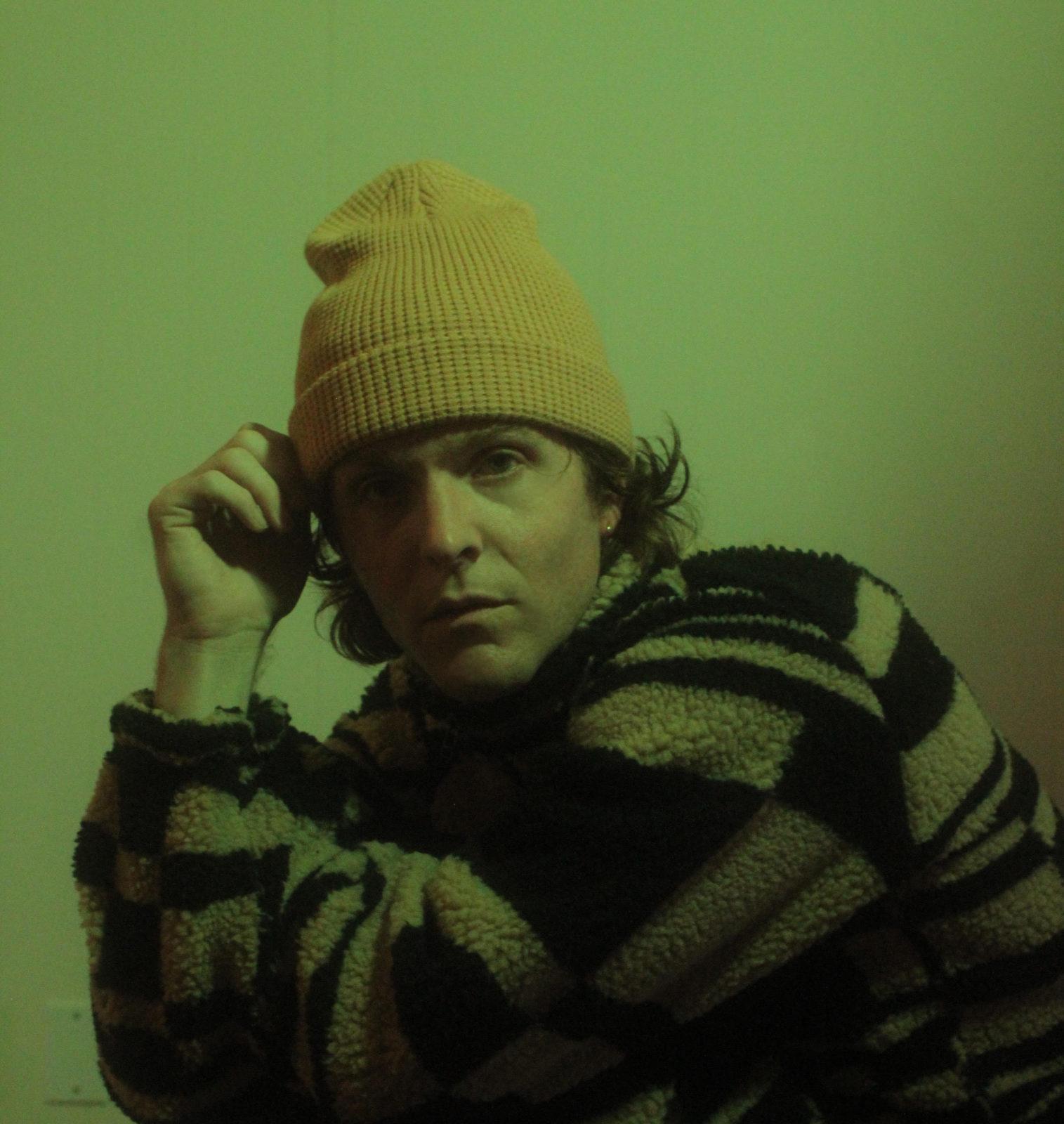 close up of man crouching in front of a black green wall