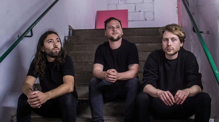 3 band members sitting on a couch