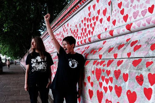 two band members standing next to a wall outside