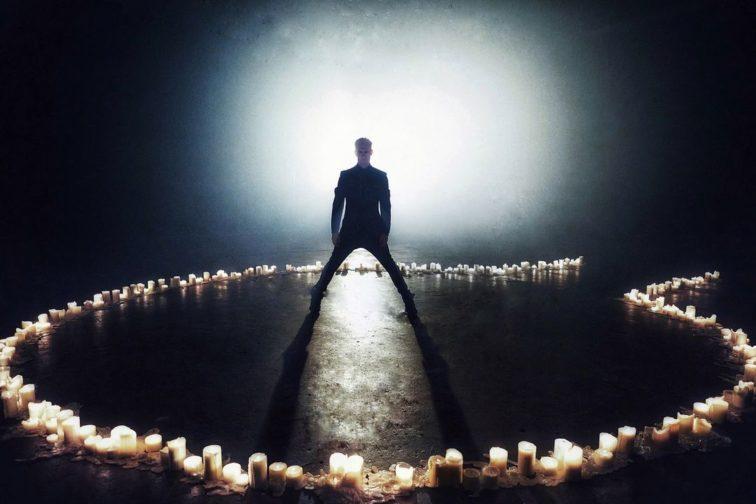 man standing on a dark stage with a ring of fire around him