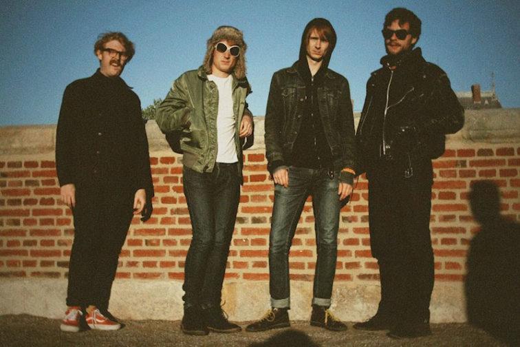 band members standing in front of a brick wall