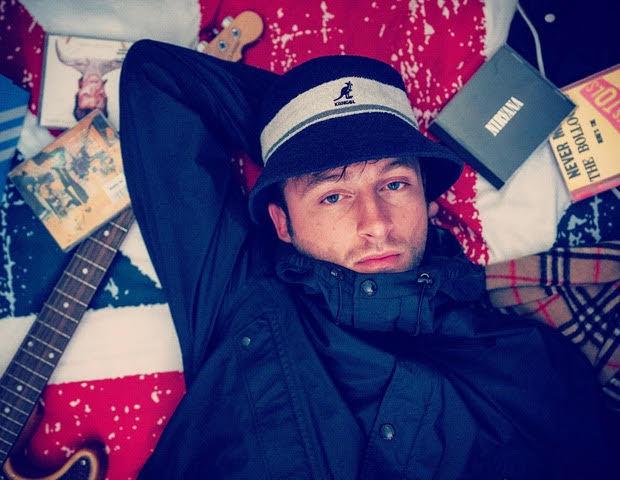 man laying down with a guitar and CD's around his head