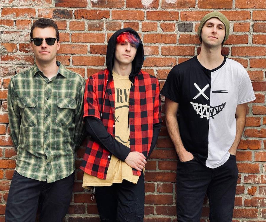 3 band members standing in front of a brick wall