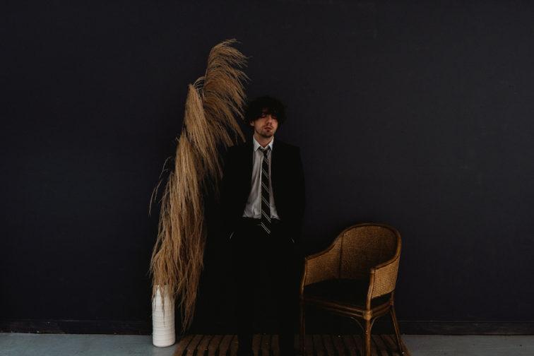 man standing in front of a dark grey wall