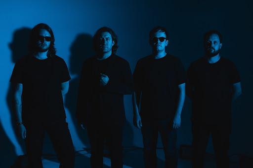 band band members standing in front of a blue wall