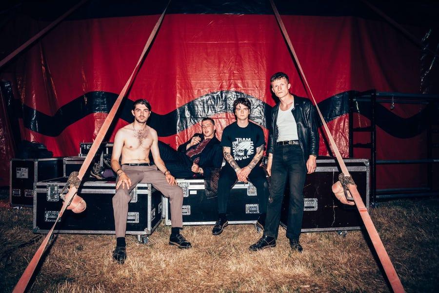 band members sitting in front of a red tarp
