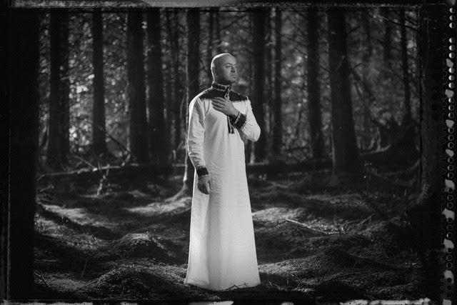 man wearing a white robe standing in the forest