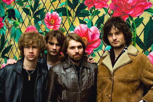 4 band members standing next to each other in front of flowers
