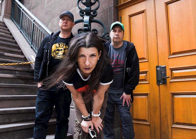 3 band members standing in front of a door