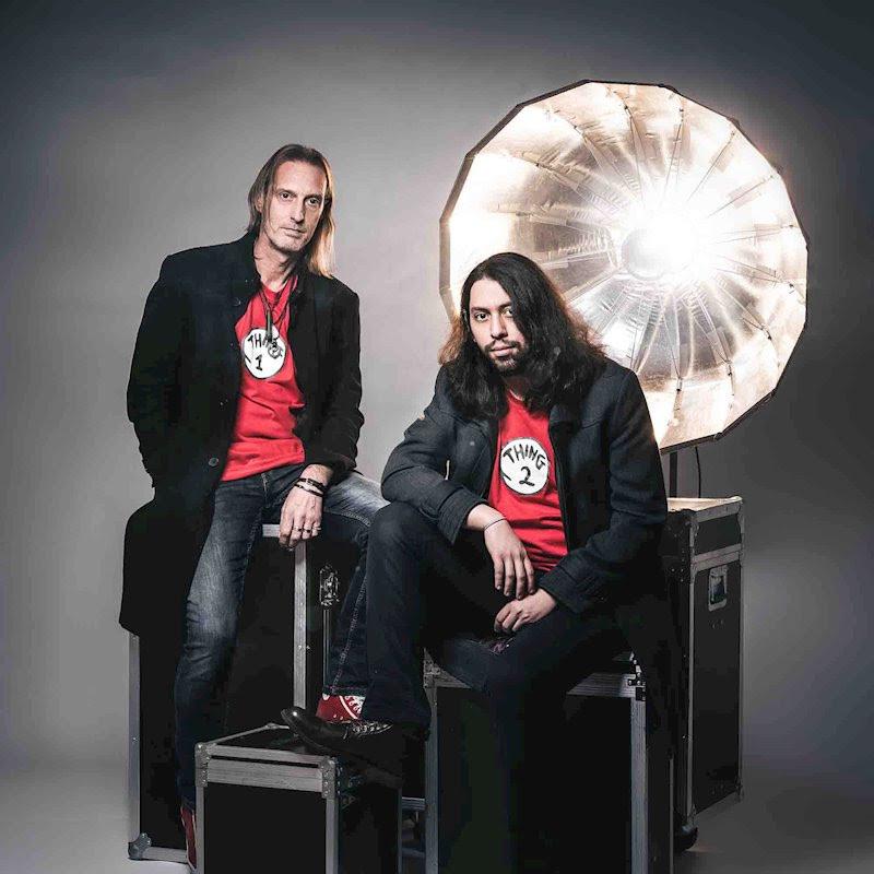 two band members sitting on equipment boxes