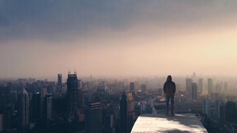 man standing on the edge of a tall building at sunset