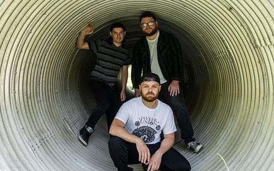 3 band members standing in a metal tube