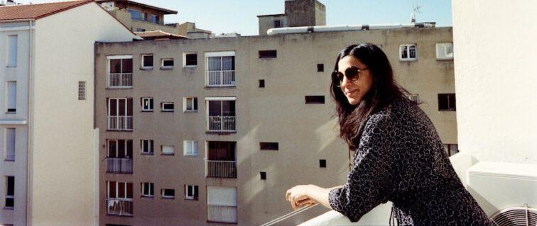 woman looking out a balcony of a tall building in the city
