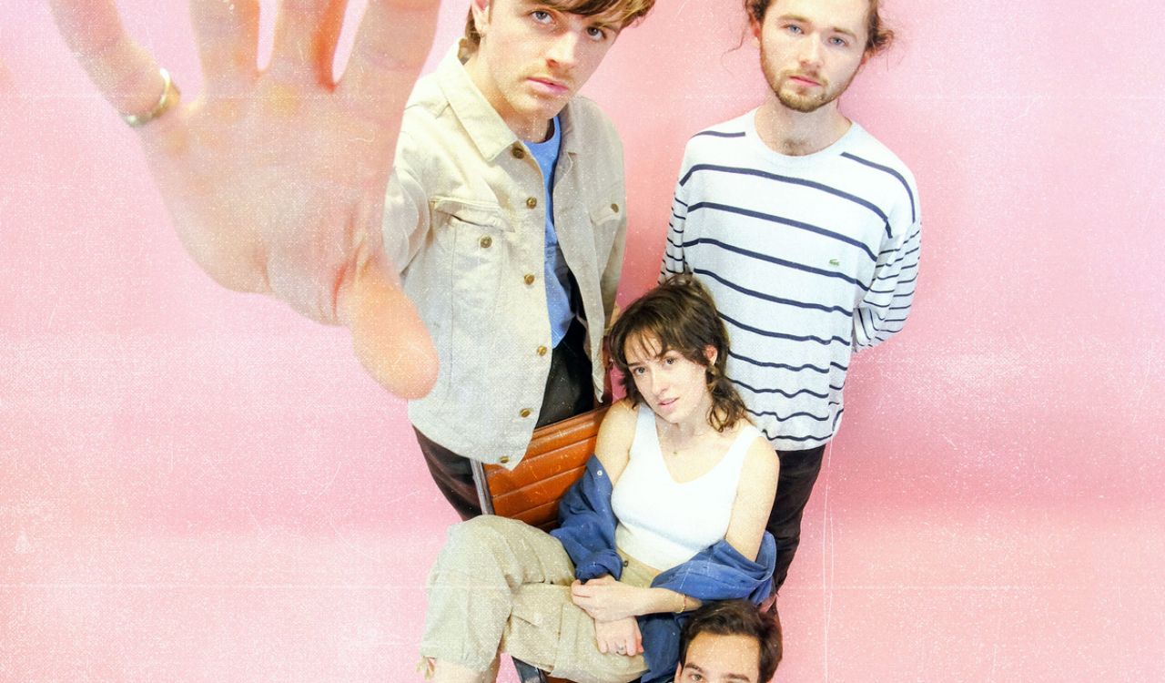 4 band members in front of a pink wall
