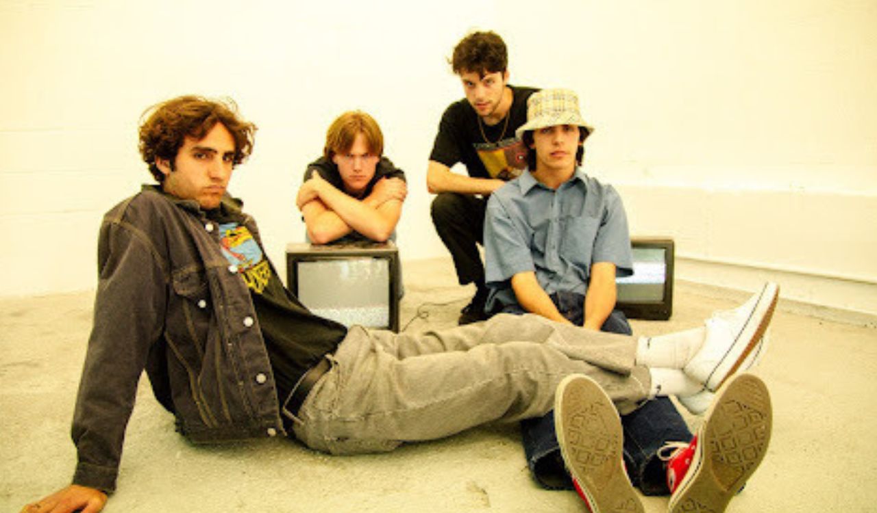 4 male band members sitting on the floor