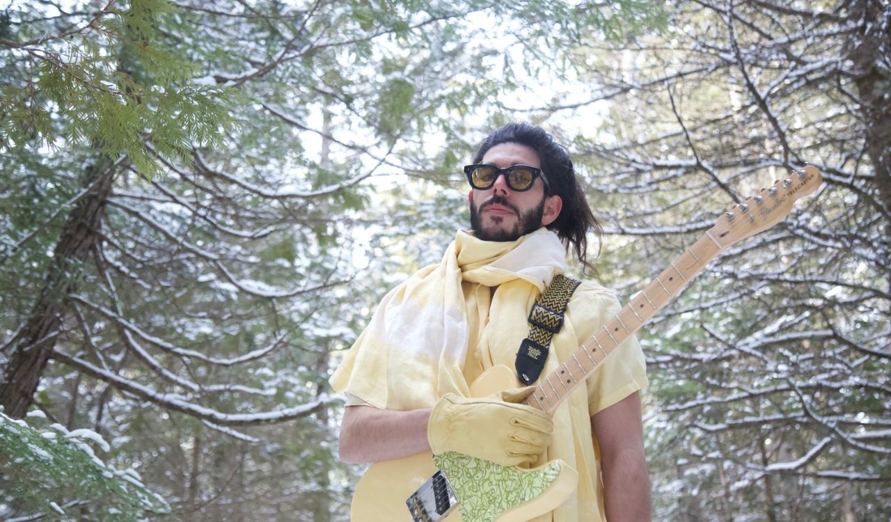 man holding a guitar in the forest
