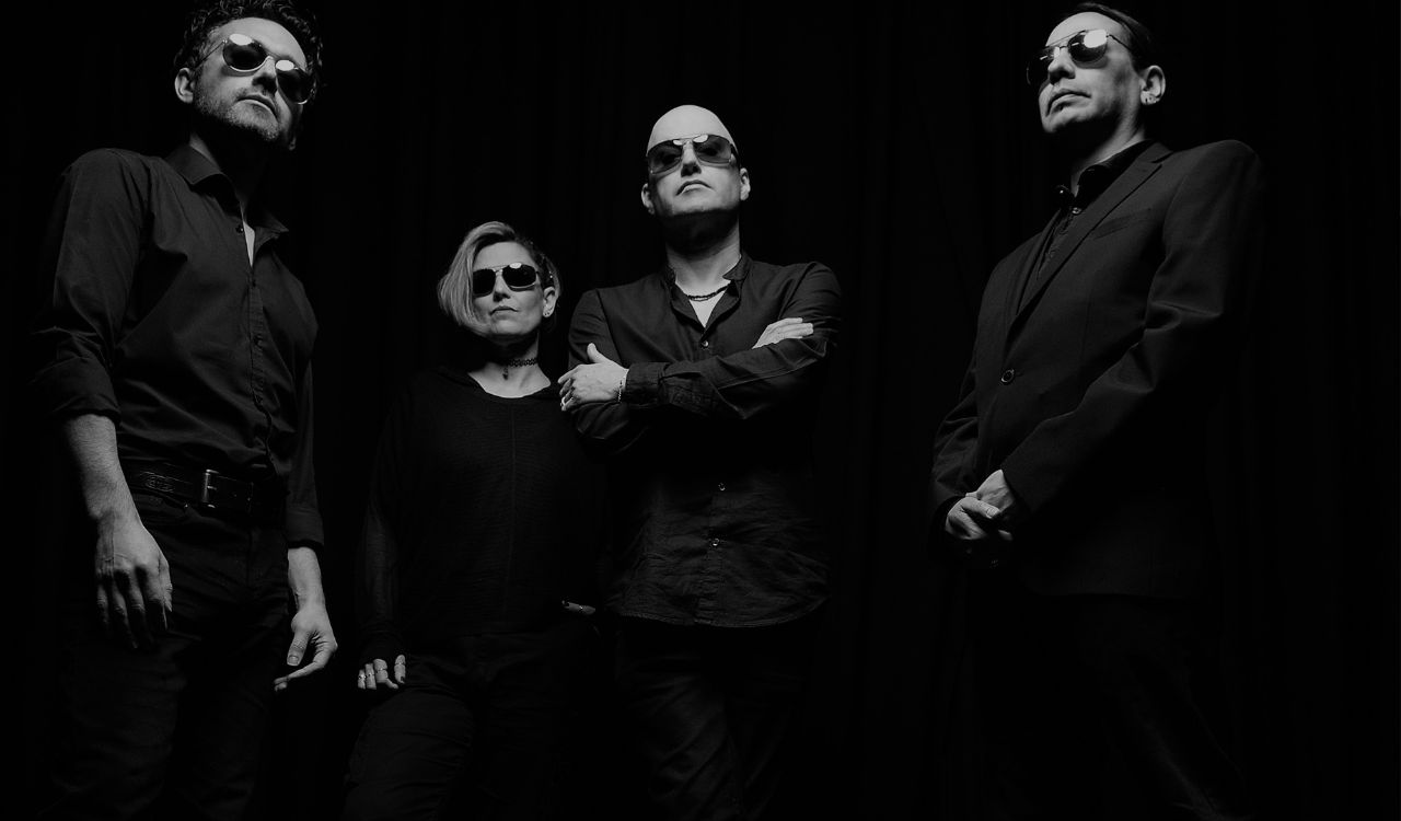 4 band members standing in a dark room