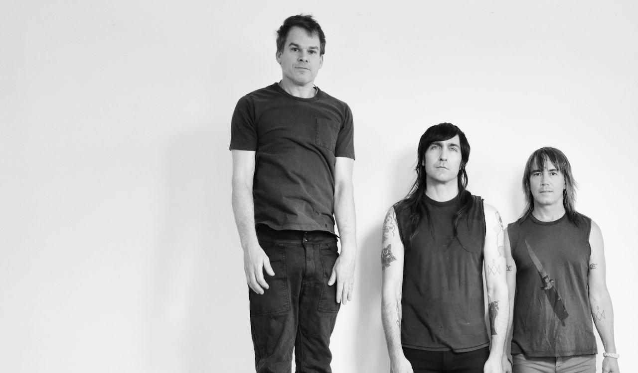 3 band members standing in front of a blank white wall
