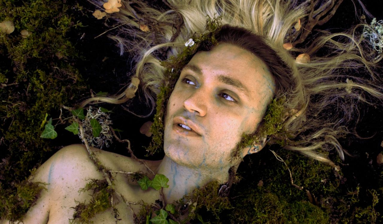 man laying down covered with moss