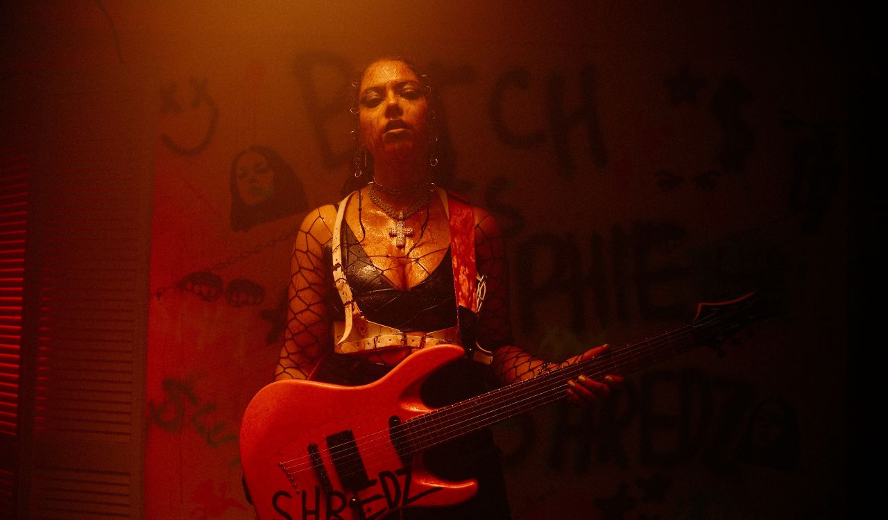 woman standing under a red light holding a guitar