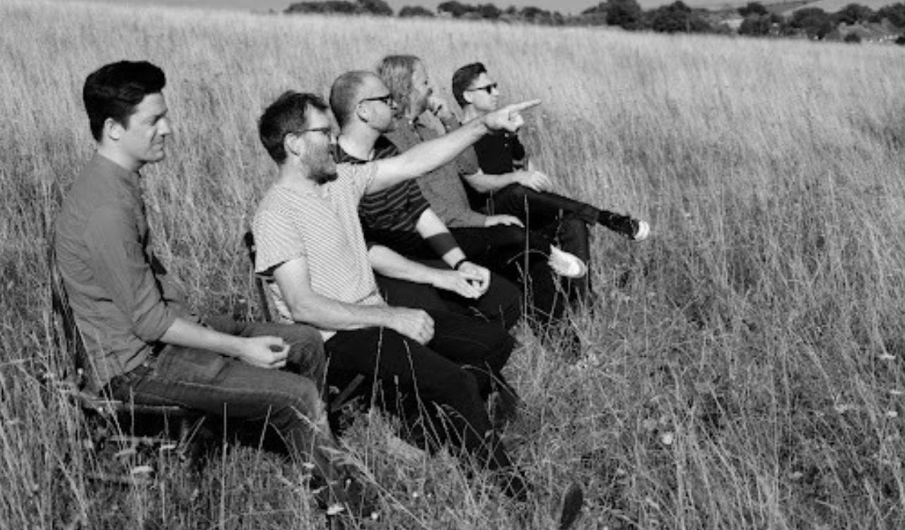 band members sitting in a field outside