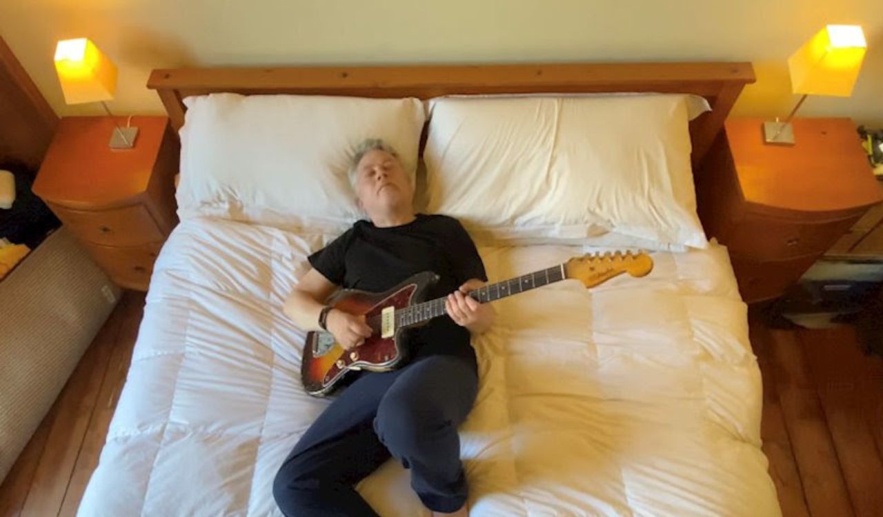 man laying on a bed with a guitar