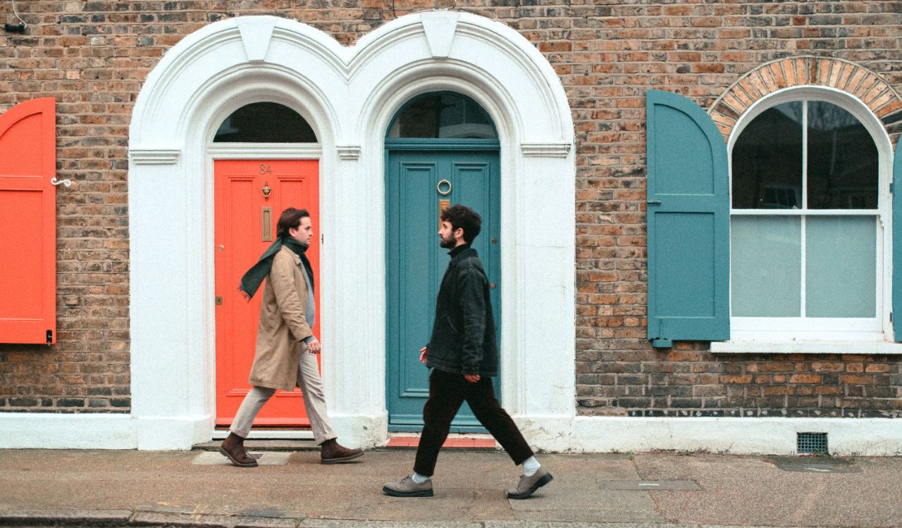 two men walking in front of a brick building