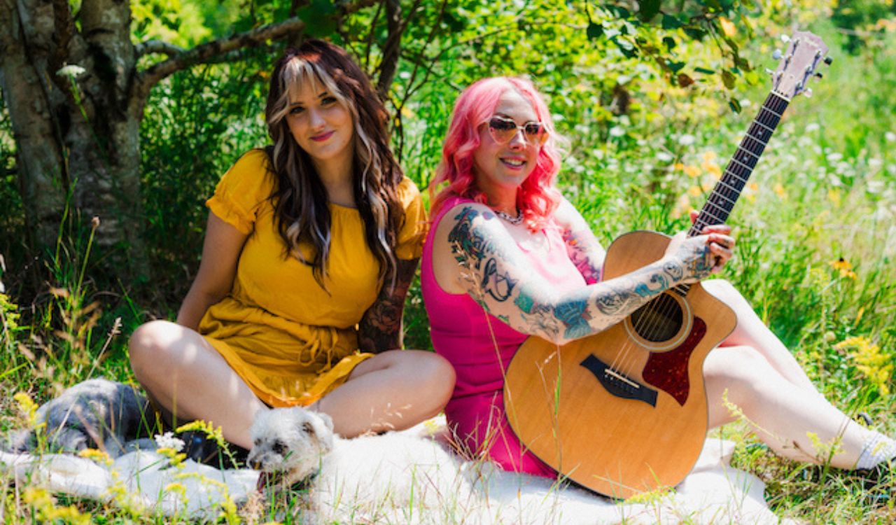two women playing guitar ans sing outside