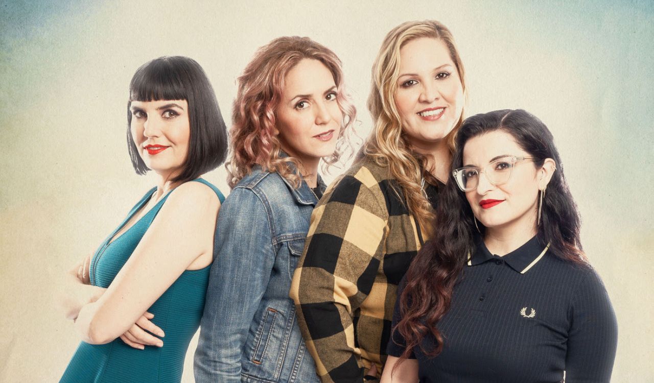 4 female band members standing in front of a cream colored backdrop