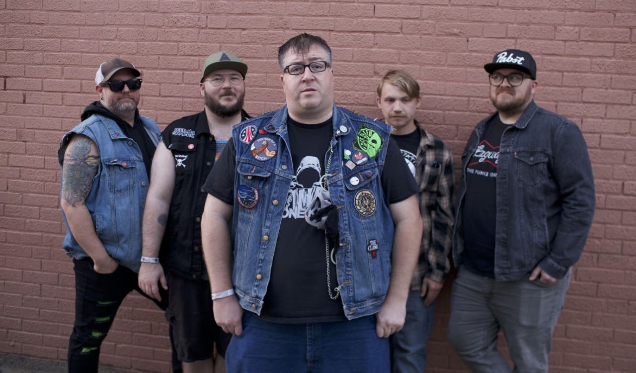 band standing in front of a brick wall