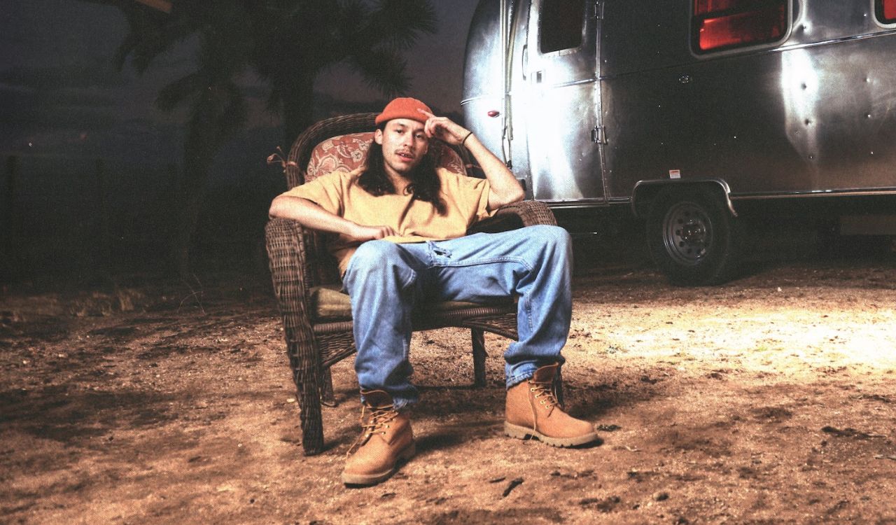 singer sitting in a chair outside a trailer