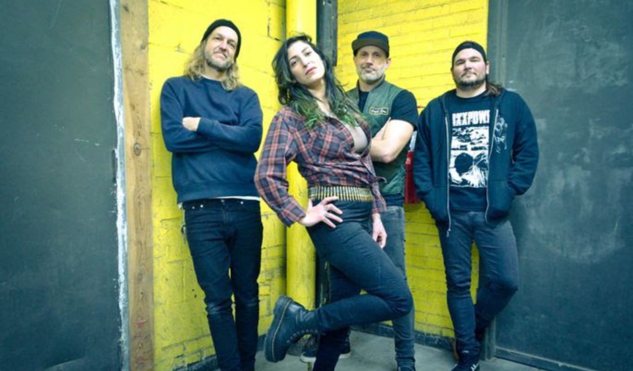 band standing in front of a yellow wall