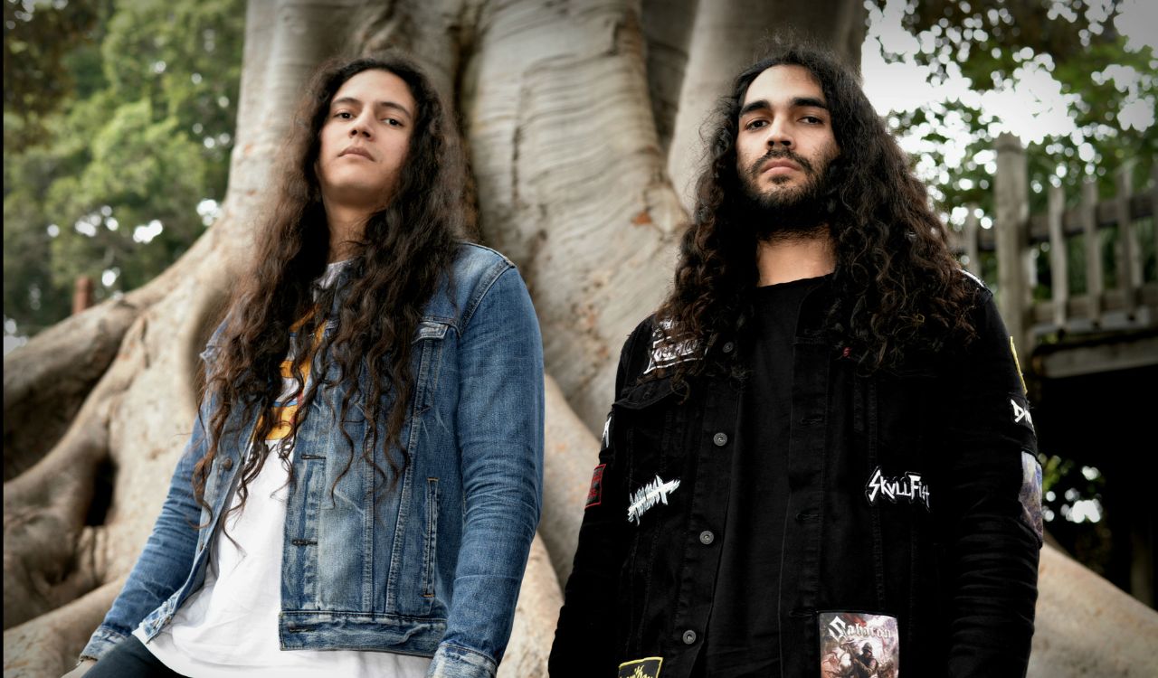 two musicians standing on front of a big tree