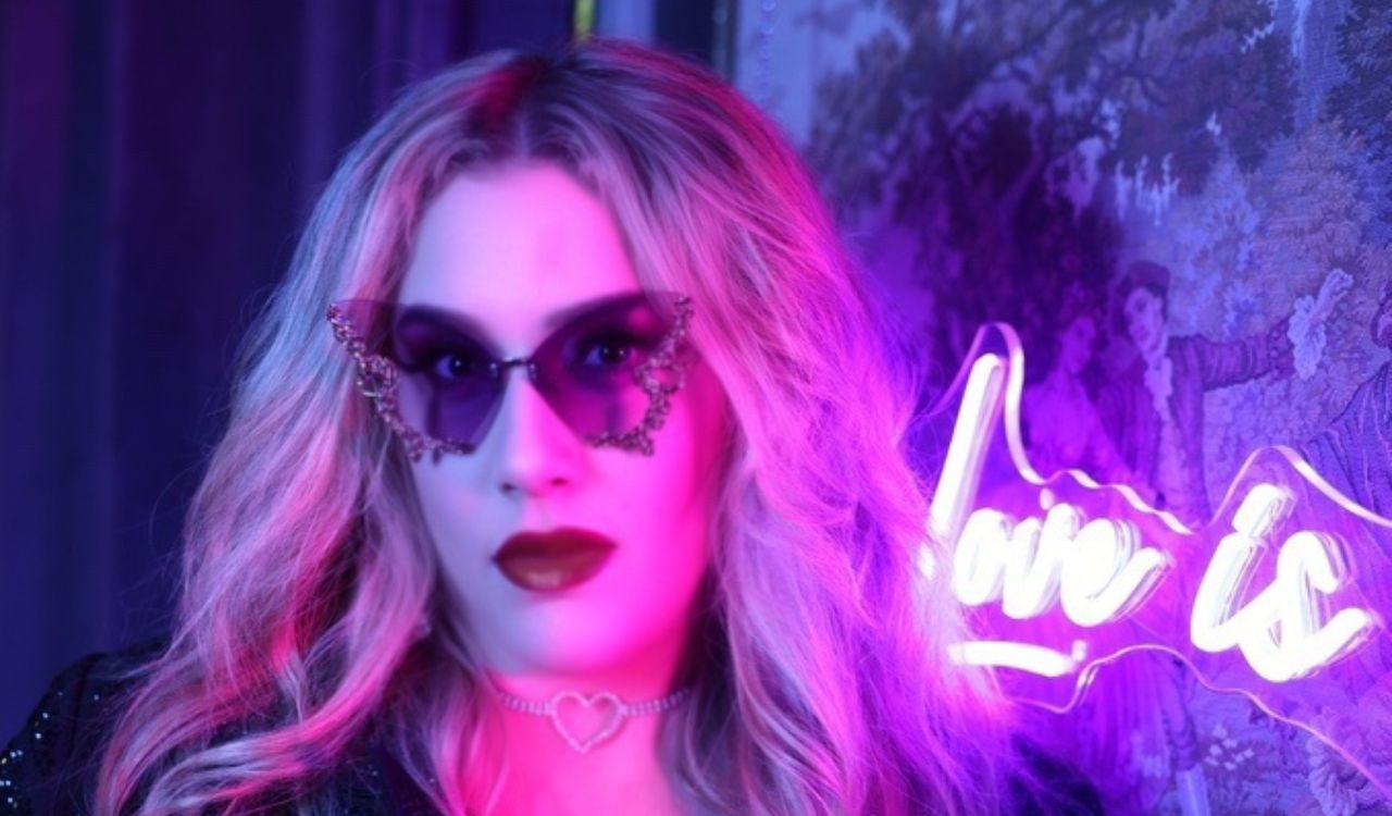 singer wearing sunglasses next to a neon light