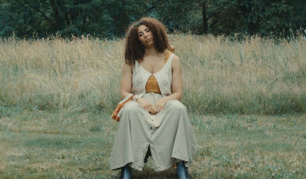 singer sitting in a chair in a field