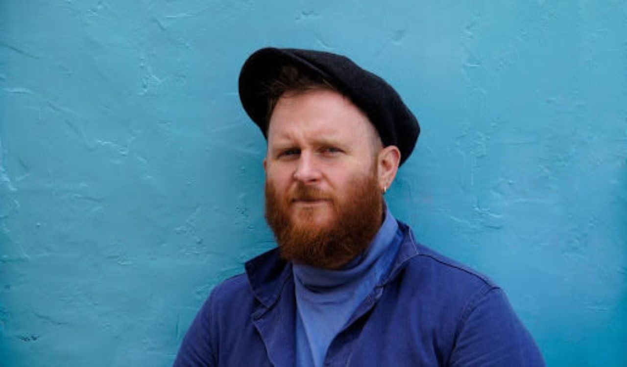 male singer standing in front of a blue wall