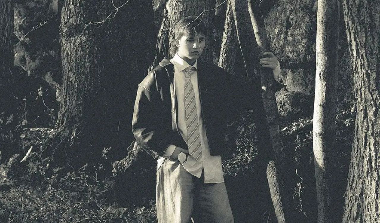 male singer standing in the woods