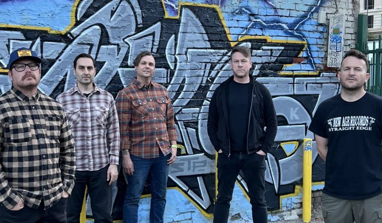 band standing outside in front of a brick wall