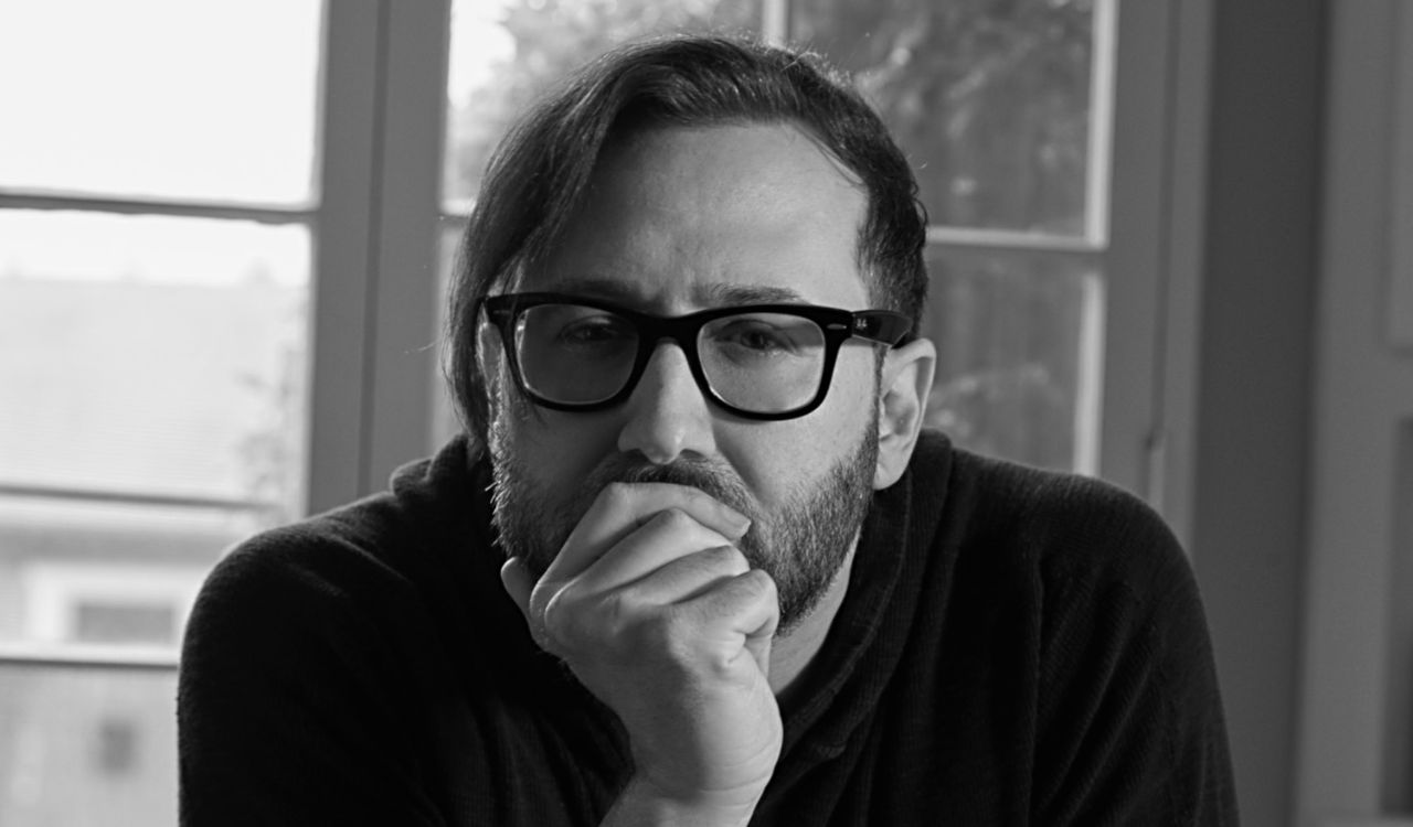 male singer leaning on a table