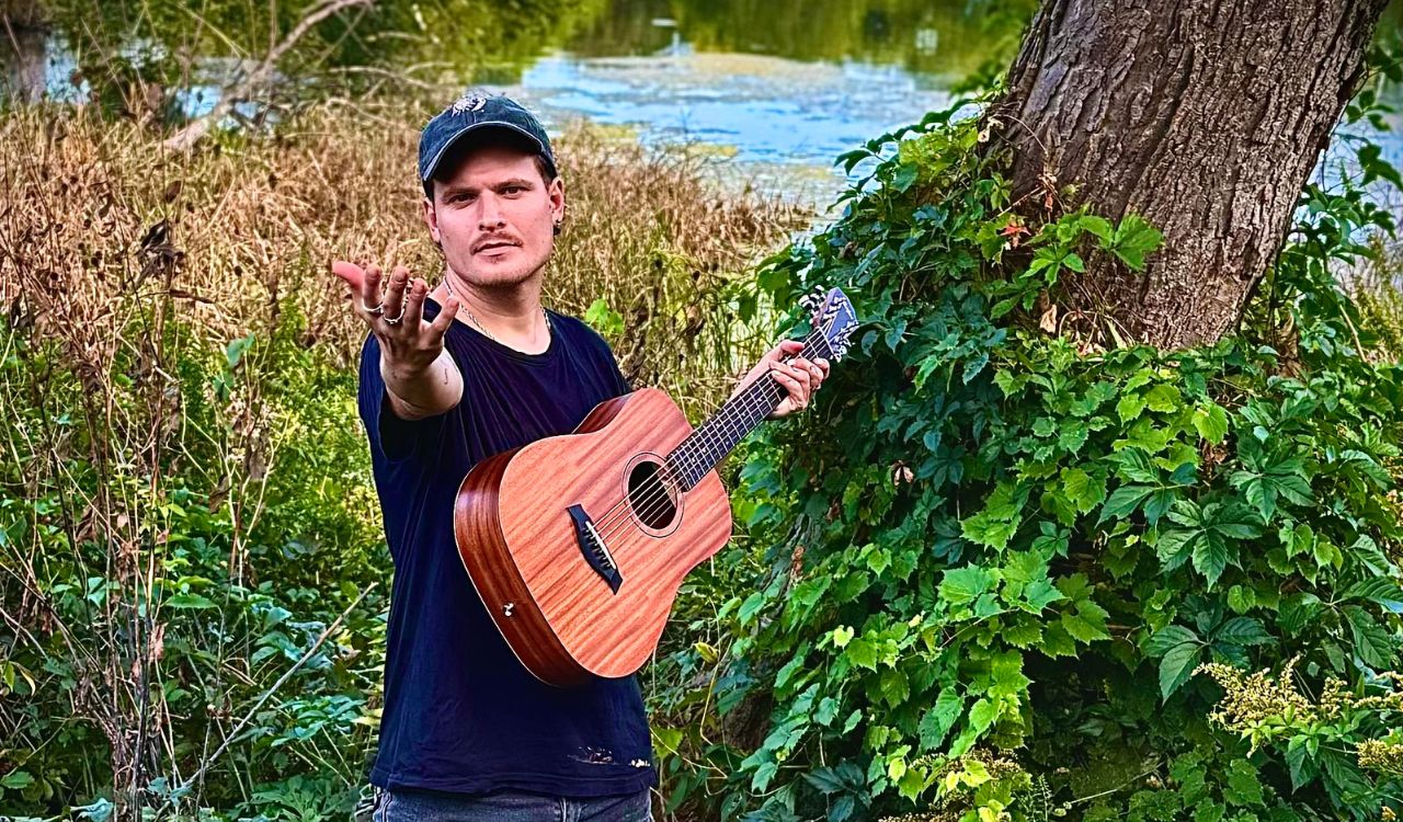 man outside holding a guitar