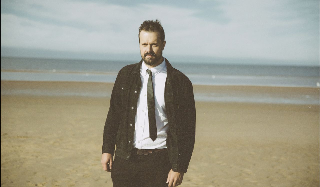 male singer standing on an empty beach